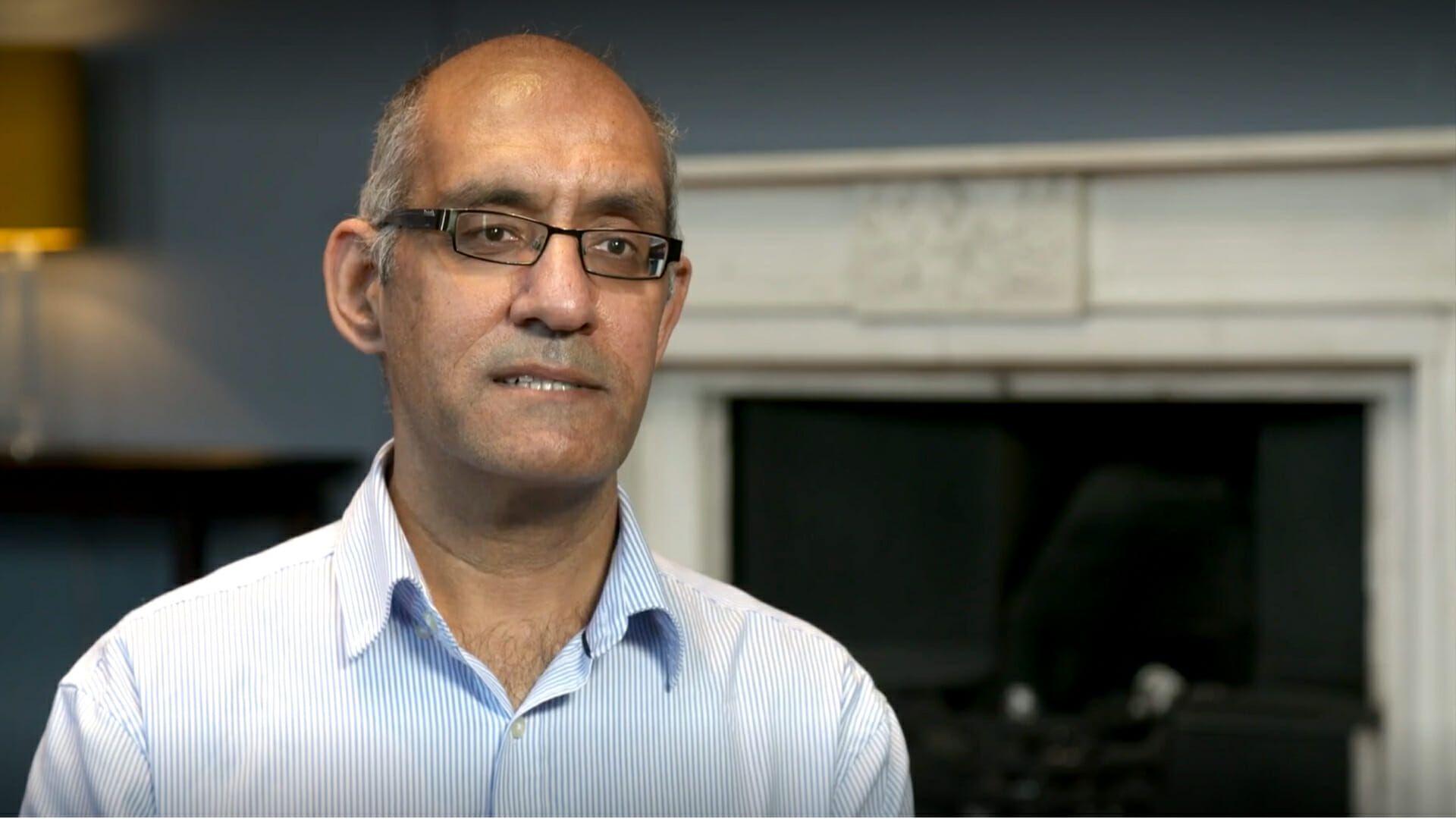 Dr Zamat sitting in front of fireplace